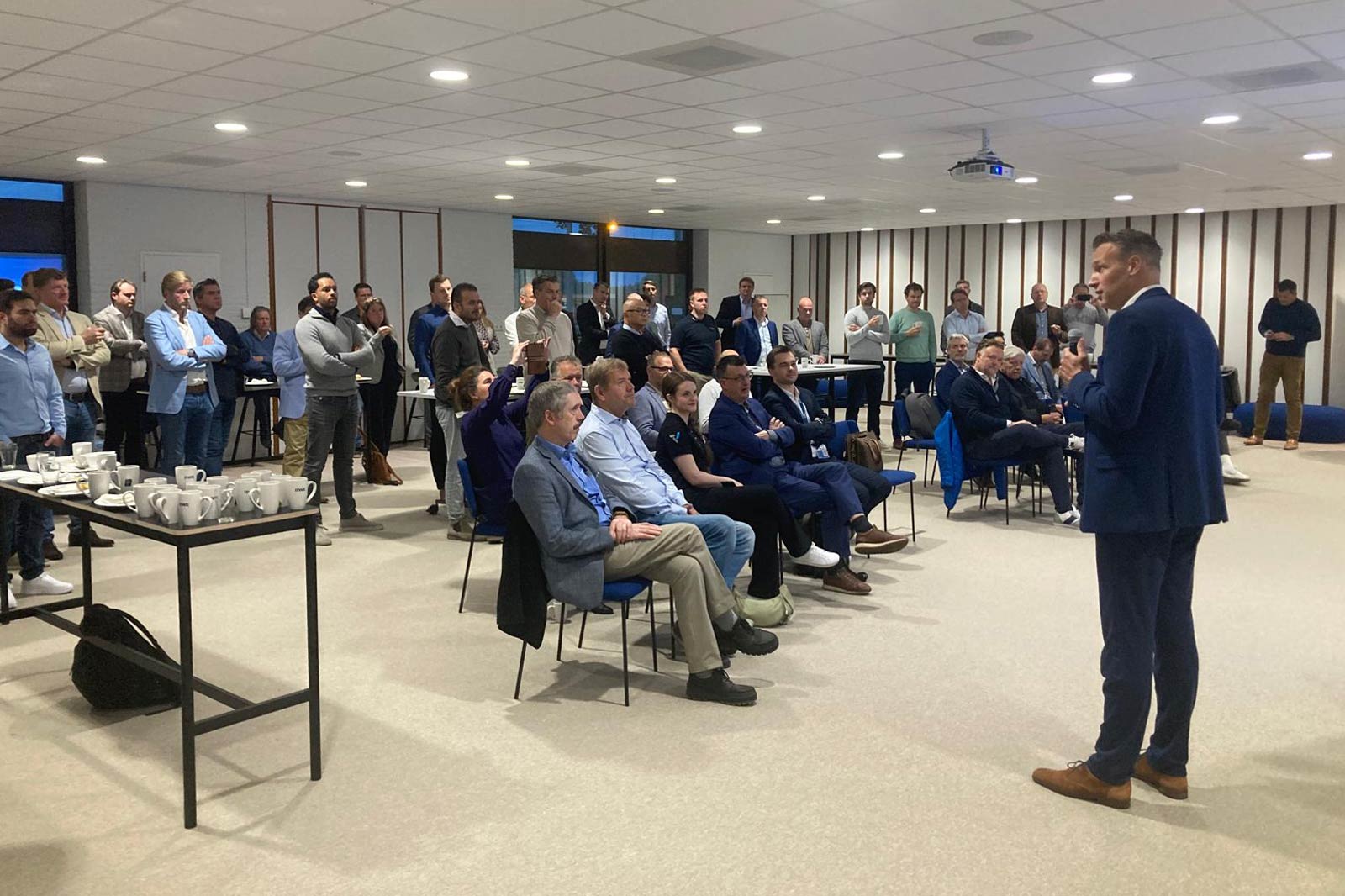 A group of professionals attentively listening to a speaker in a modern conference room.