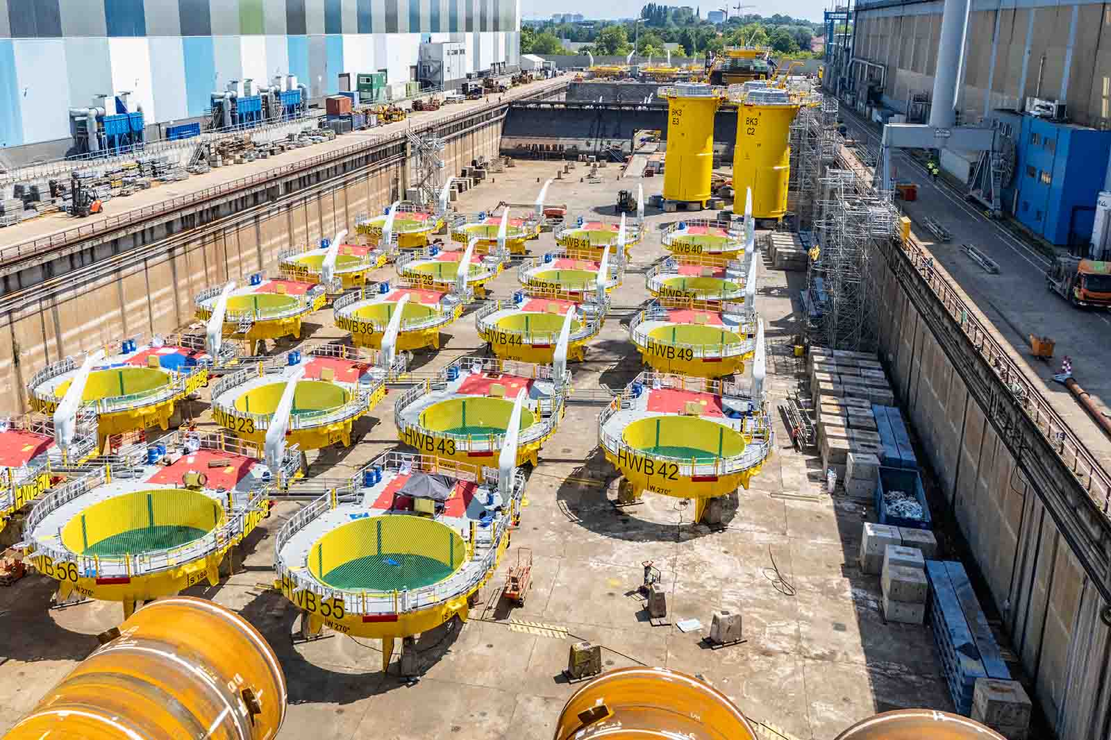 A large industrial storage yard with multiple yellow, circular structures arranged in rows inside a concrete enclosure.